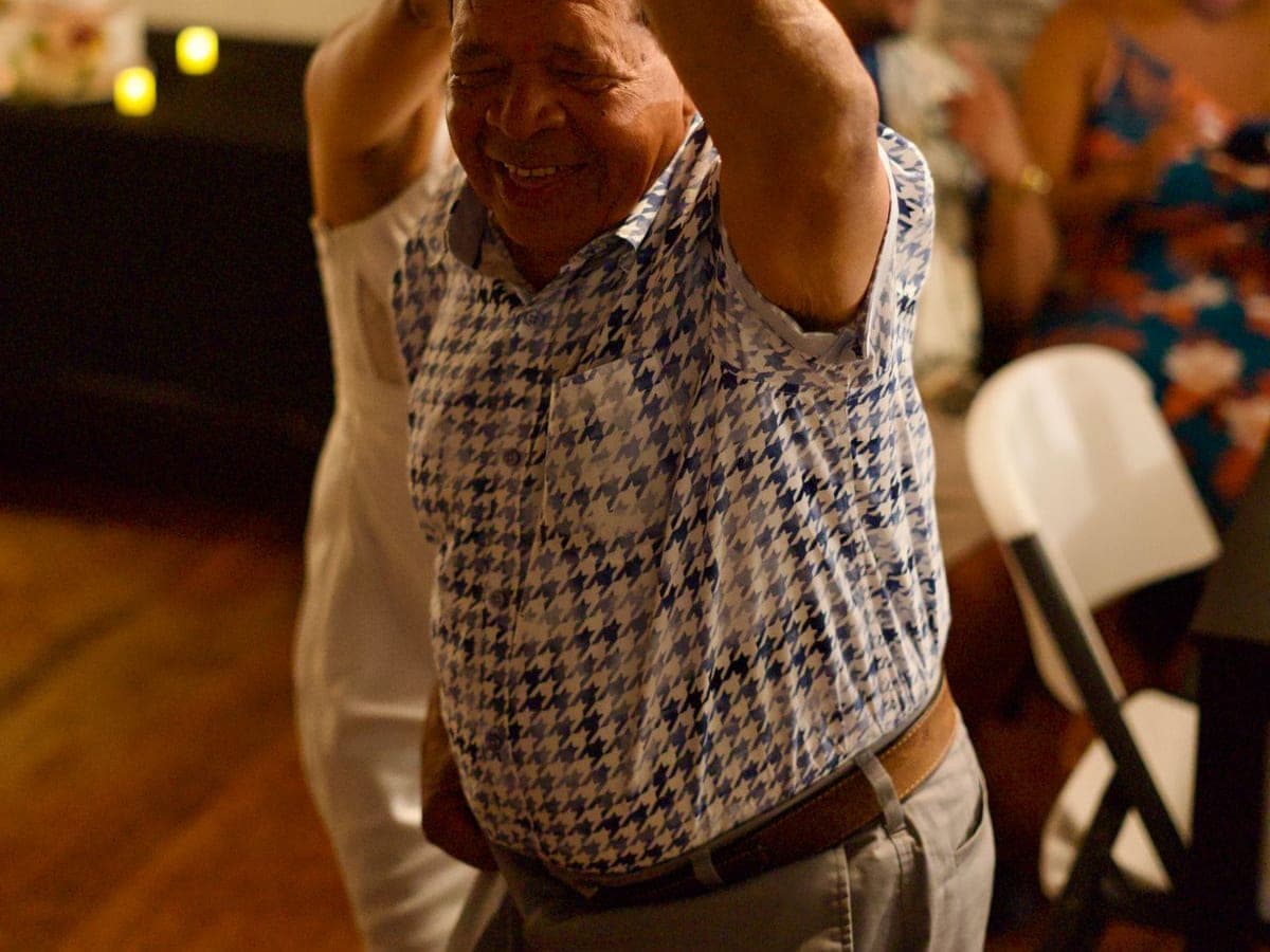 A mature wedding guest dancing happily at an indoor reception.